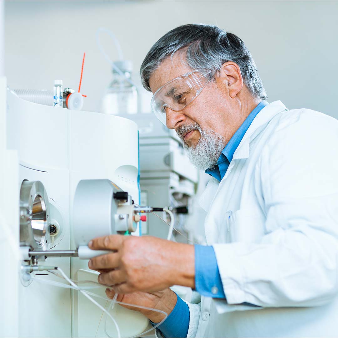 A doctor is working on a biomedical device with eye protection glasses.